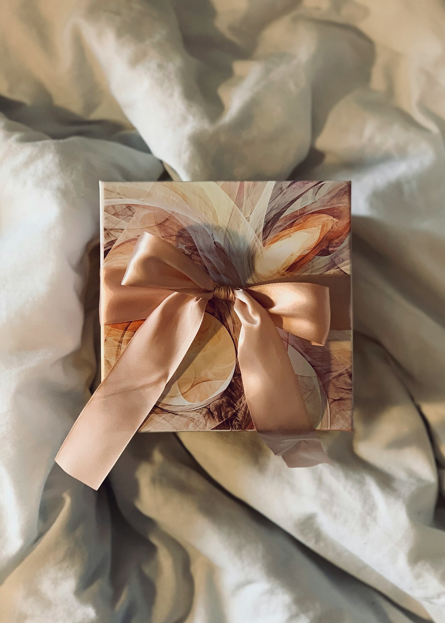 Caja de regalo envuelta con lazo sobre tela clara