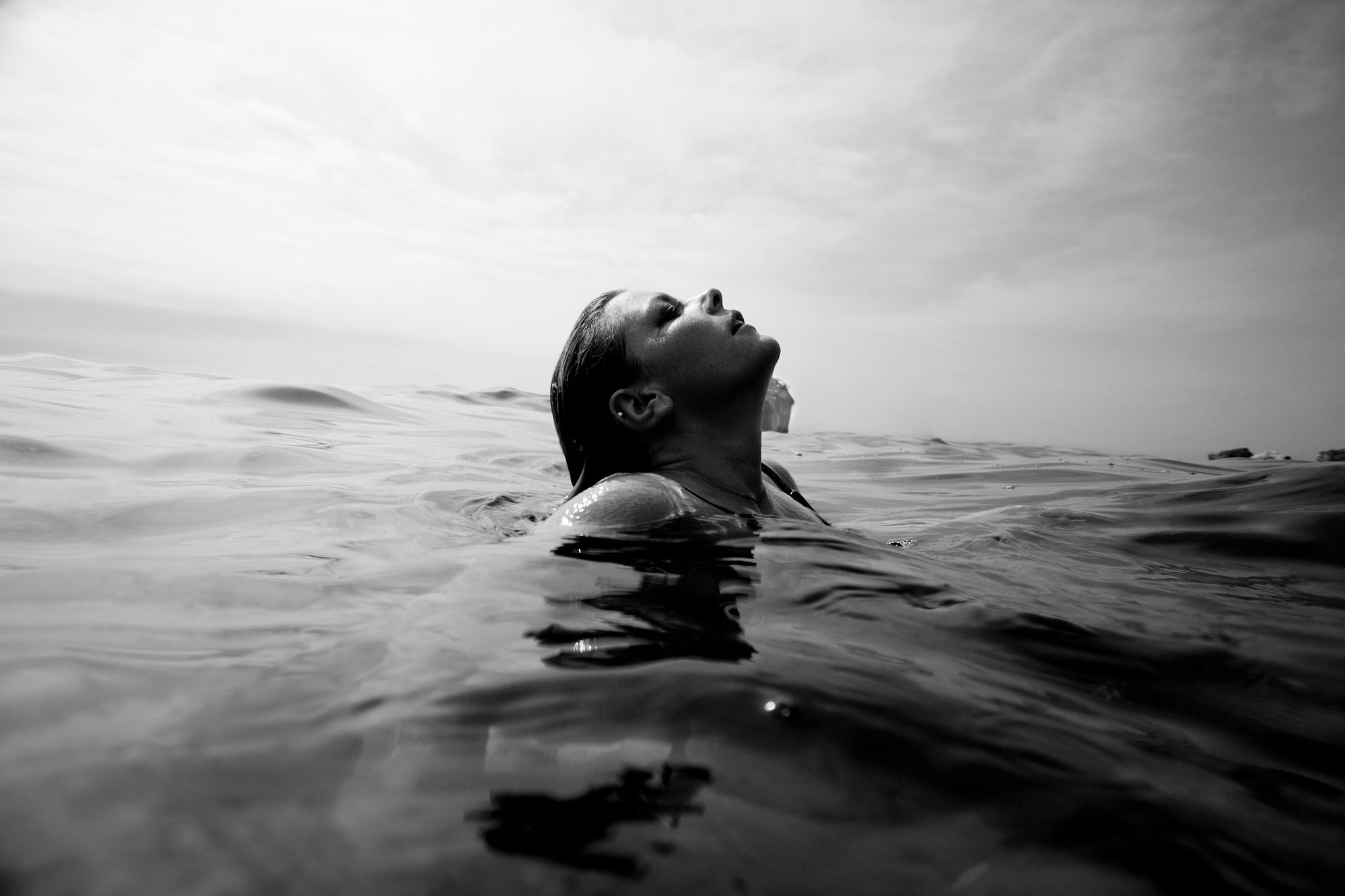Rostro relajado asomando en la superficie del agua, en blanco y negro